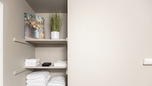 Baño con estantes blancos que sostienen toallas y una planta en maceta.