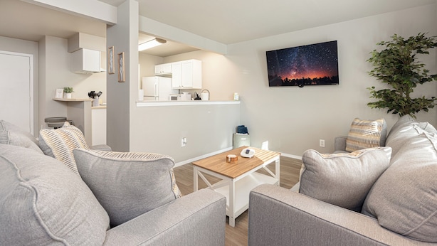 Una sala de estar moderna con un sofá, una mesa de centro y una cocina al fondo.