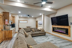 Un vaste espace de vie comprenant un canapé d’angle, une cheminée, des meubles en bois et un téléviseur.