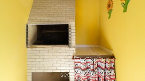 A room with a brick fireplace, yellow walls, and a patterned curtain. - Apt w/ 2 Bedrooms and Barbecue Grill Fdc0005 (Florianópolis)