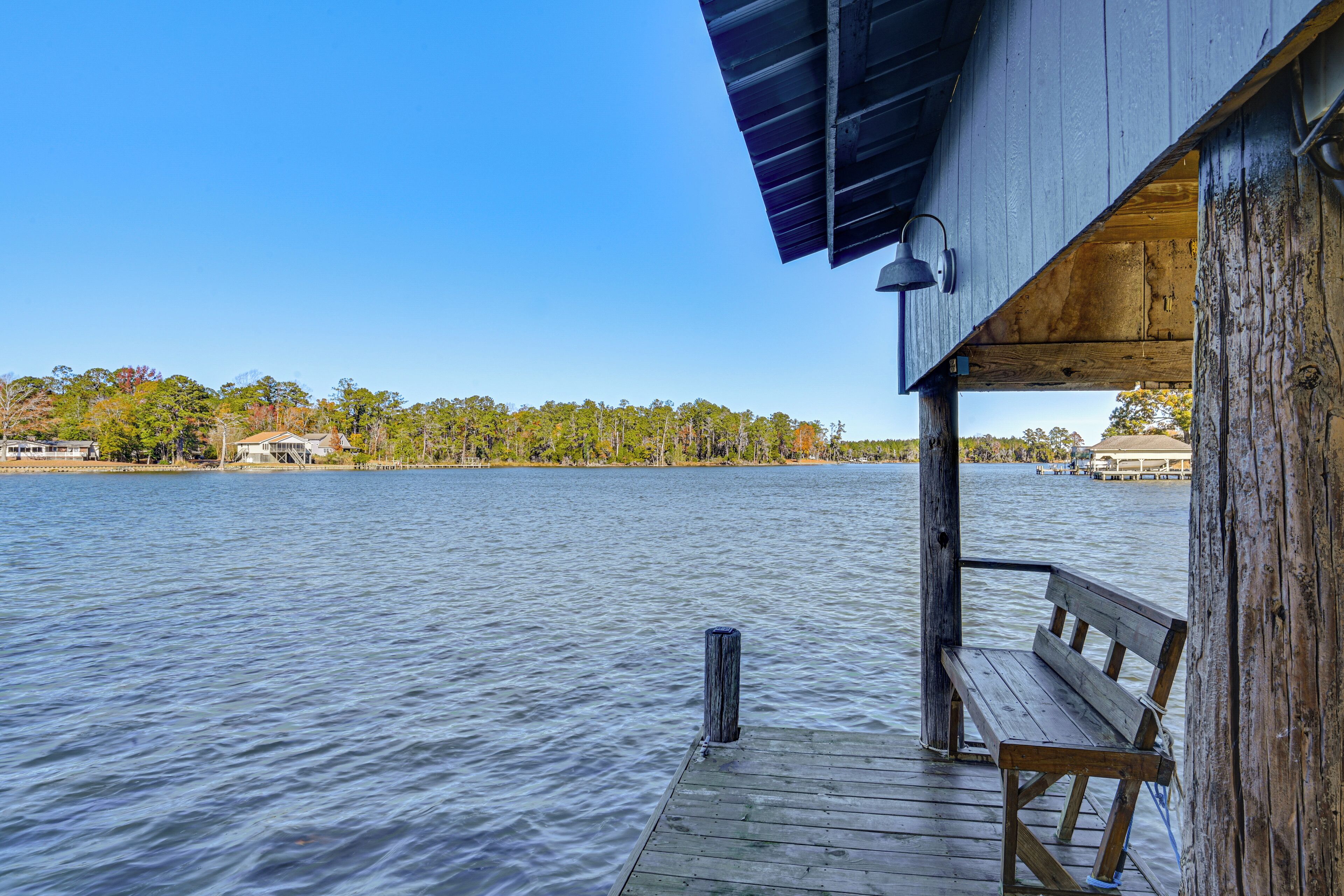 A wooden pier extending into a calm lake with a bench and a lamp post.