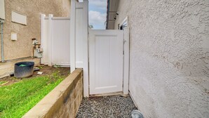 A narrow alleyway with a white door, a concrete planter with grass, and a gravel path. - 4 Mi to RUHS! Pet-Friendly Apt w/ Grill (Moreno Valley)