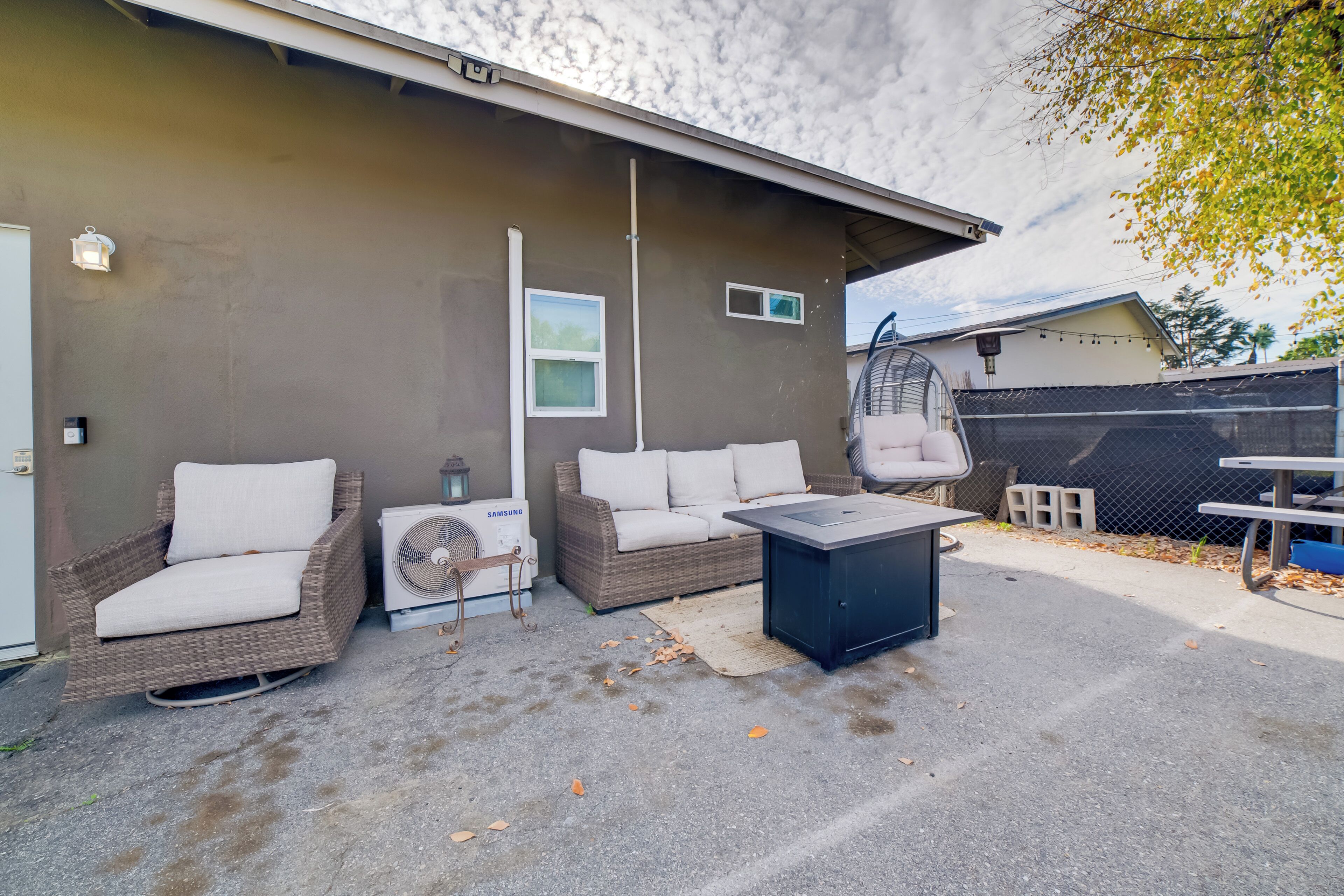 An outdoor patio area with wicker furniture, a table, and a fan.