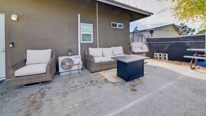 Un espace extérieur aménagé en terrasse, avec des meubles en osier, une table et un ventilateur.