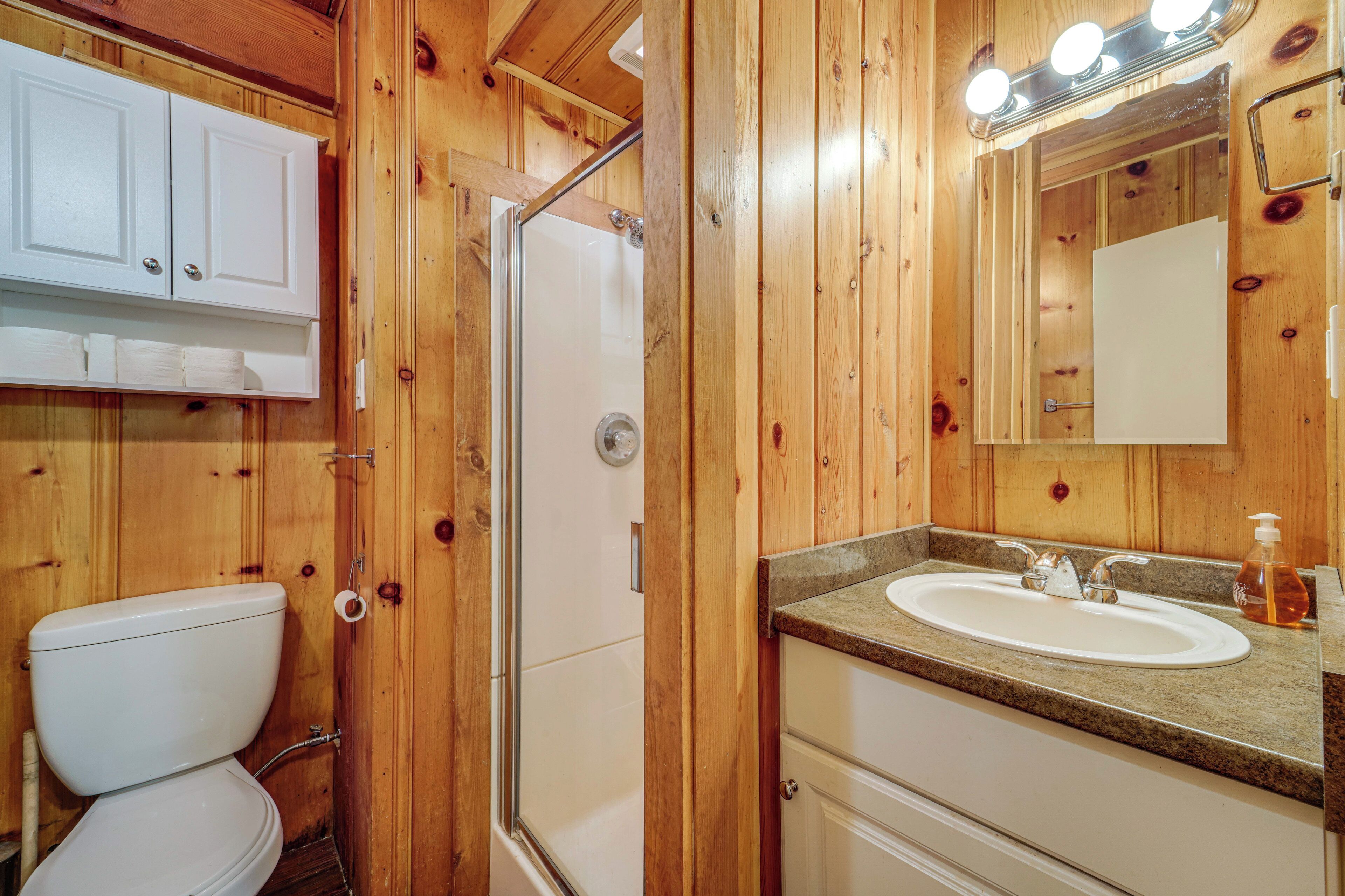 Un baño de madera con inodoro, lavamanos y ducha.