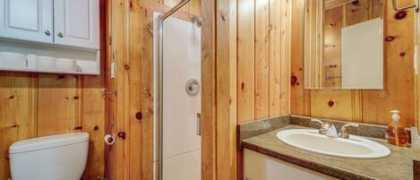 Un baño de madera con inodoro, lavamanos y ducha.