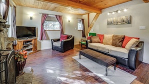 A cozy living room with a wooden ceiling, a flat-screen TV, a sofa, a chair, and a fireplace. - Near Slopes, Donner Lake & Trails! Woodsy Retreat (Truckee)