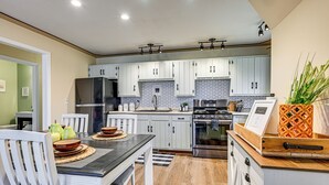 Una cocina moderna con armarios blancos, un refrigerador de acero inoxidable y una encimera de madera.