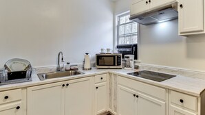 A kitchen with white cabinets, a stainless steel sink, a microwave, a coffee maker, and a window with a view of trees. - Hike & Sip in North Georgia: Apartment w/ Deck (Alto)