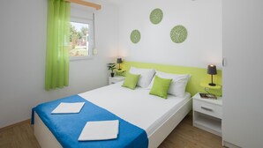 Habitación de hotel ordenada con cama, dos mesitas de noche, una ventana con cortinas y un muro con diseños circulares decorativos.