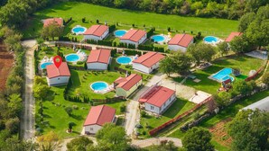 Vista aérea de una zona residencial con varias casas, cada una con piscina y tejado de tejas rojas.