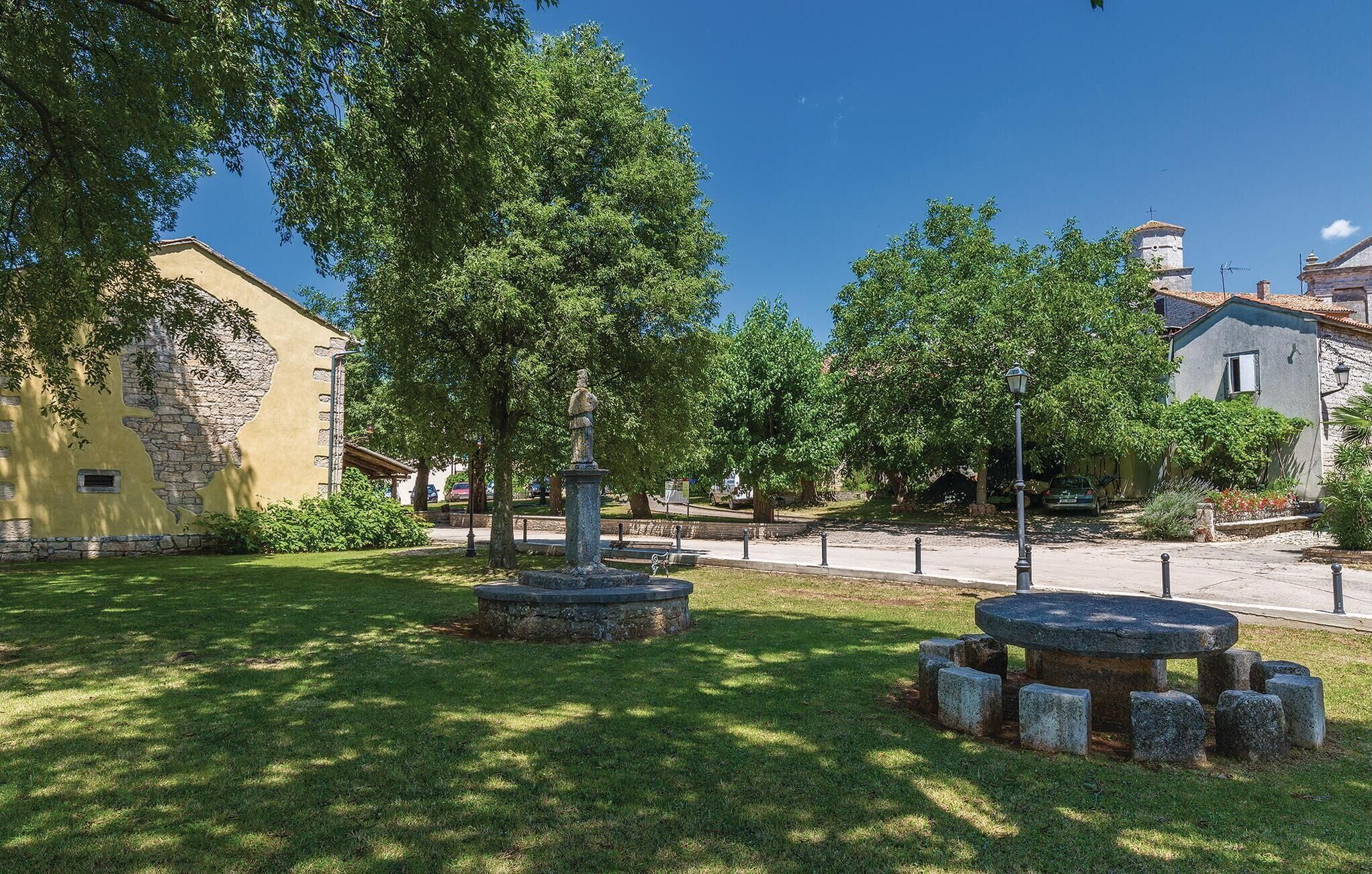 A courtyard with stone benches, a statue, and a building with a stone facade.