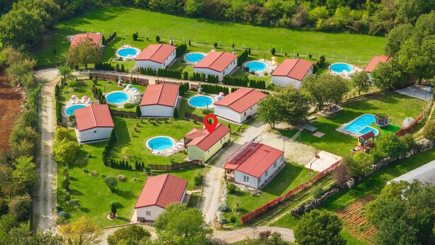Vista aérea de una zona residencial con varias casas, cada una con piscina y tejado rojo.