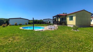 Una propiedad residencial con piscina, patio cubierto y pequeño jardín.