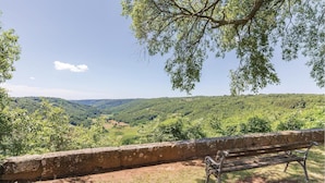 Un banco con vistas a un paisaje montañoso, lleno de vegetación exuberante y un cielo despejado.
