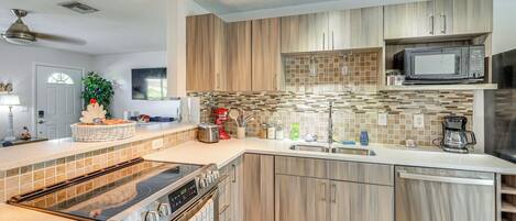 A modern kitchen with a large island, stainless steel appliances, and wooden cabinetry.