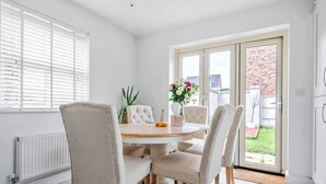 Un comedor con una mesa redonda, cuatro sillas y vistas al exterior mediante un ventanal.