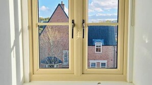 Una ventana con un visillo oscuro, dos cristales y un alféizar blanco.