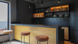 Eine moderne Küche mit dunkler Spritzschutzwand, einer Holztresen und Pendelleuchten.