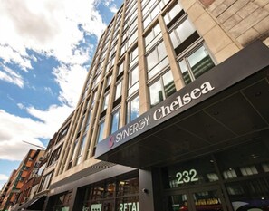 A building with a sign reading "SYNERGY Chelsea" and the number "232" indicating a retail space.