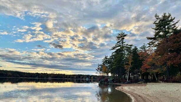 A calm lake with a dirt path and trees reflecting in the water. - Winnipesaukee Retreat | Hot Tub | Suissevale Beach (Moultonborough)
