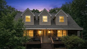 A two-story house with a porch, a front door, and a staircase leading to the entrance. - Winnipesaukee Retreat | Hot Tub | Suissevale Beach (Moultonborough)