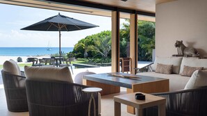 Un área de estar al aire libre moderna con mobiliario de mimbre, una mesa central para café y una sombrilla grande que proporciona sombra.