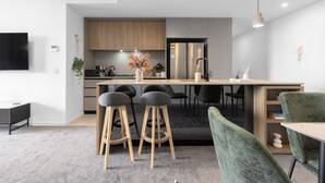Eine moderne Küche mit Holzschränken, einem Edelstahlkühlschrank und einer zentralen Kochinsel mit Hockern.