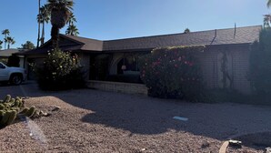 A house with a brick exterior, a gravel driveway, and a white car parked in the driveway. - Charming 3-bedroom house with AC in sunny Scottsdale (Scottsdale)