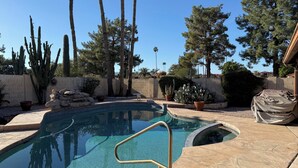 A swimming pool with clear water, surrounded by cacti and trees. - Charming 3-bedroom house with AC in sunny Scottsdale (Scottsdale)