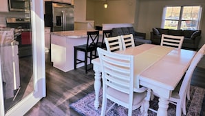 A modern kitchen with a central island, white cabinetry, and stainless steel appliances.