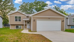 A two-story residential building with a garage, a front porch, and a well-maintained lawn.