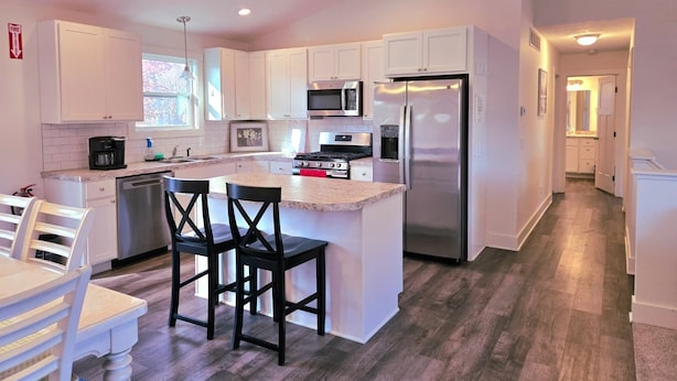A modern kitchen with white cabinets, stainless steel appliances, and a central island with bar stools.