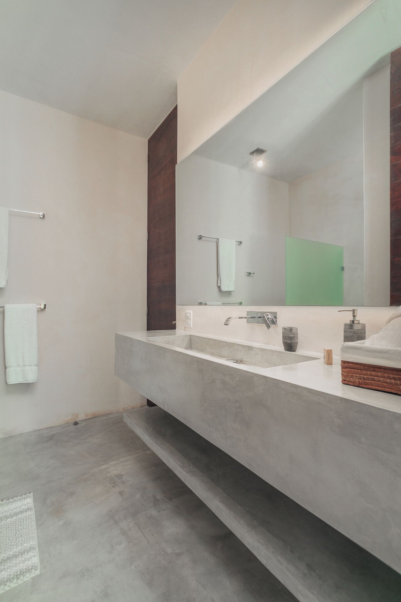 A modern bathroom with a large mirror, two sinks, and a wooden door.