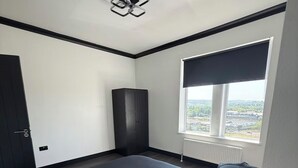 Ein Schlafzimmer mit einem großen Bett, einem Kleiderschrank, einem Heizkörper und einem Fenster mit Blick.