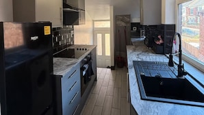 Eine moderne Küche mit schwarzen Geräten, einer Marmorarbeitsplatte und Blick ins Freie durch ein Fenster.