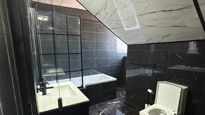 Ein modernes Badezimmer mit Duschkabine aus Glas, einem weißen Waschbecken und einer Toilette.