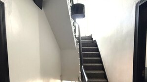 Eine Treppe mit Handlauf, die zu einem Zwischenpodest mit einer Tür rechts führt.