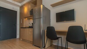 Et lille køkken med indbygget køleskab, træskabe og et fladskærms-tv på væggen.