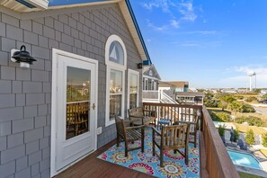 A residential deck with a wooden railing, a colorful rug, and a view of a swimming pool. - Ocean Views! New 4bd Home, very close to Beach! (Oak Island)