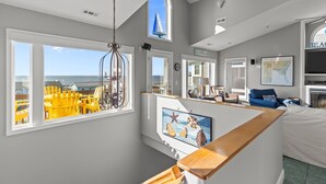 Ein Zimmer mit Meerblick, ein großes Fenster, eine Holzbank und ein gerahmtes Bild von Muscheln.