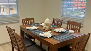 Un coin repas avec une table et des chaises en bois, une machine à café et une vue par la fenêtre.