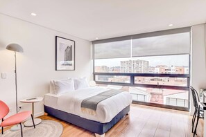 Een moderne slaapkamer met een groot raam, een bed, een stoel en een vloerlamp.