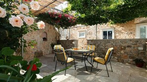 An outdoor patio with stone walls, a table, and four chairs. - 1 bedroom pet friendly apartment in Bol (Bol)