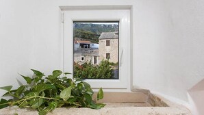A window with a view of a stone building and greenery outside. - 1 bedroom pet friendly apartment in Bol (Bol)