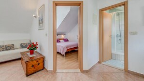 A bedroom with a bed, a wooden chest of drawers, a potted plant, and a bathroom with a shower. - 1 bedroom pet friendly apartment in Bol (Bol)