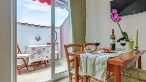 Un comedor con una mesa lista para dos personas, una botella de vino y una orquídea en maceta.