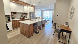 Une cuisine moderne dotée d’un îlot central, de meubles en bois, d’appareils électroménagers en acier inoxydable et d’un coin repas avec une table et des chaises.