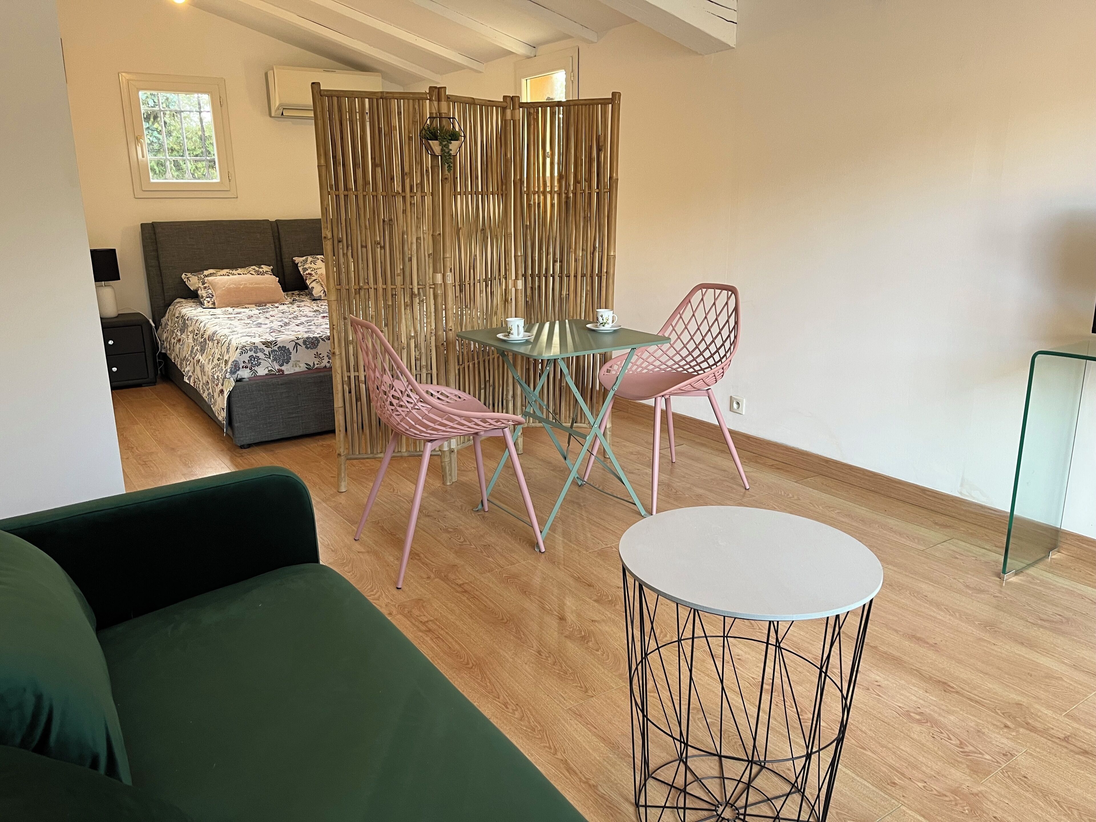 A modern room with a bed, a green sofa, a dining table with chairs, and a small round table.
