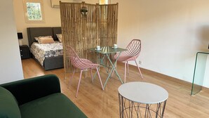 Et moderne værelse med en seng, en grøn sofa, et spisebord med stole og et lille rundt bord.